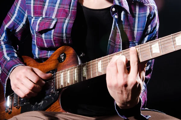 Muž, hrát na kytaru v temné místnosti — Stock fotografie