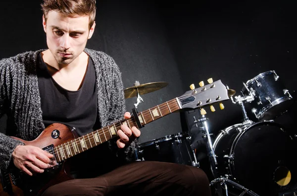 Человек играет на гитаре в темной комнате — стоковое фото