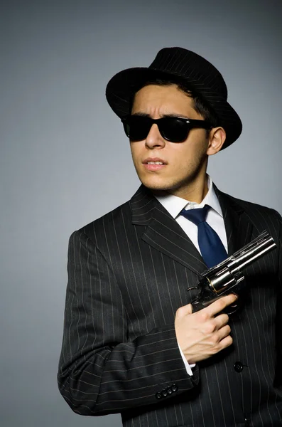 Young man in classic striped costume holding gun isolated on gray — Stock Photo, Image