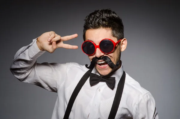 Ung man med falsk mustasch isolerade på grå — Stockfoto