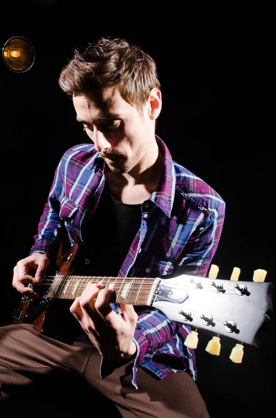 Hombre tocando la guitarra en habitación oscura — Foto de Stock