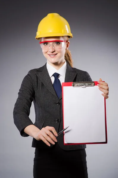 Женщина-инженер со шлемом и бумагой, изолированной на сером — стоковое фото
