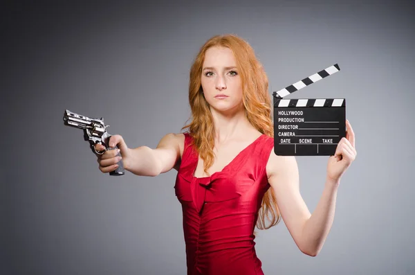 Pretty young girl in red dress with gun isolated on gray — Stock Photo, Image