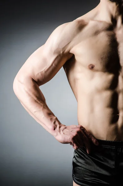 Muskulöser Mann posiert im dunklen Studio — Stockfoto