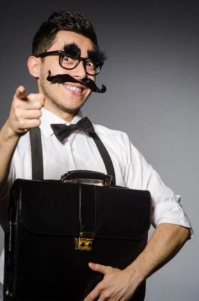 Jovem com bigode falso segurando caso isolado em cinza — Fotografia de Stock