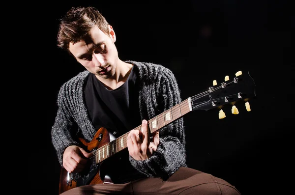 Hombre tocando la guitarra en habitación oscura —  Fotos de Stock