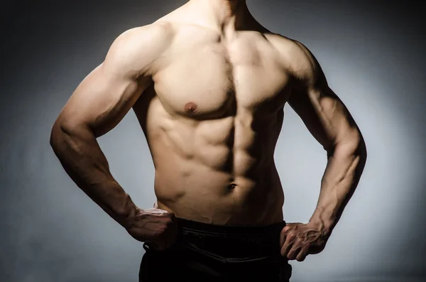 Muscular man posing in dark studio — Stock Photo, Image