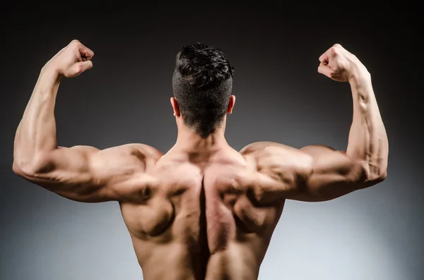 Muscular man posing in dark studio — Stock Photo, Image