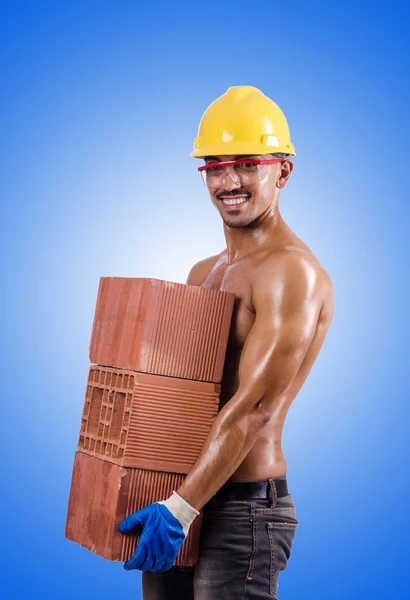 Muscular builder with bricks against the gradient — Stock Photo, Image