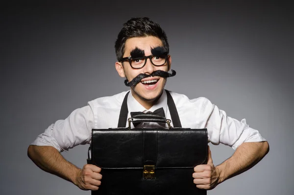 Jovem com bigode falso segurando caso isolado em cinza — Fotografia de Stock