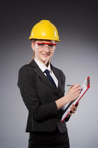 Female engineer with helmet and paper isolated on gray — Stock Photo, Image