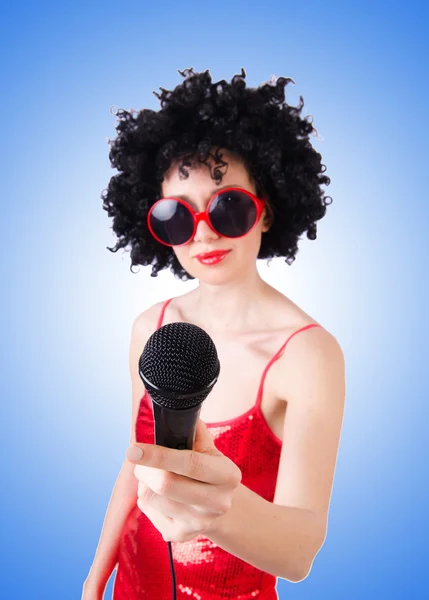 Поп звезда с микрофоном в красном платье против градиента — стоковое фото