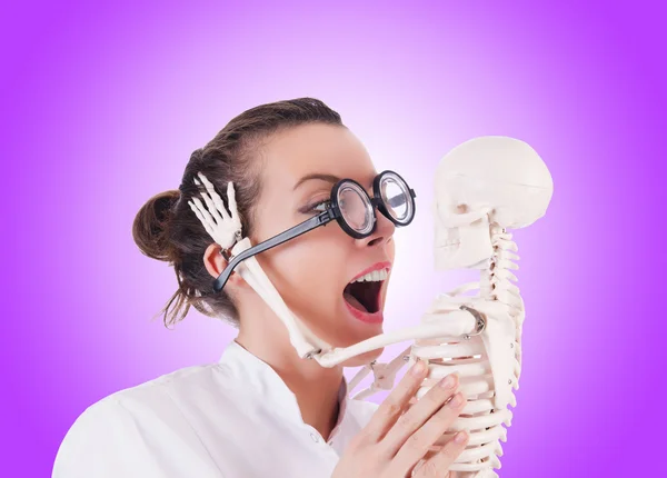 Doctor with skeleton against gradient — Stock Photo, Image