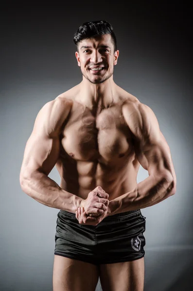 Muscular man posing in dark studio — Stock Photo, Image