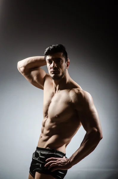 Muscular man posing in dark studio — Stock Photo, Image