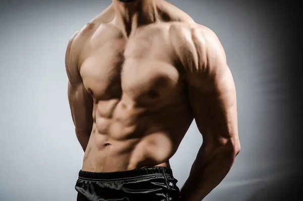 Muscular man posing in dark studio — Stock Photo, Image