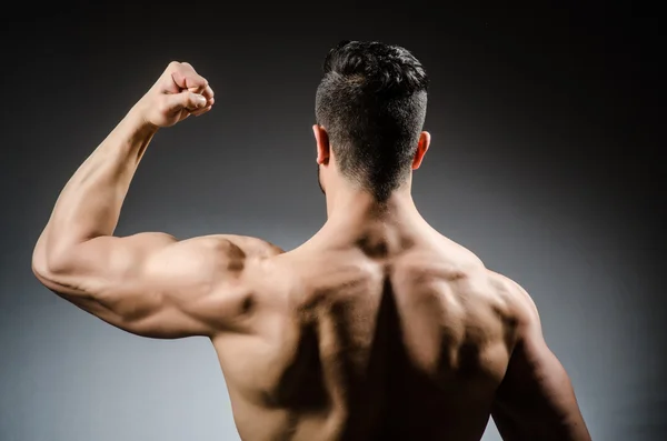 Muscular man posing in dark studio — Stock Photo, Image