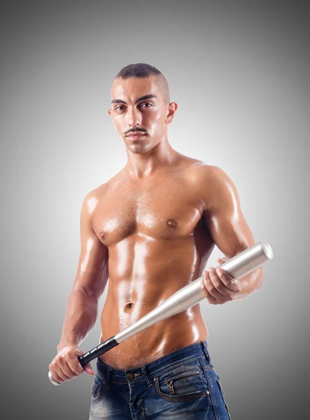 Muscular man with baseball bat against gradient — Stock Photo, Image