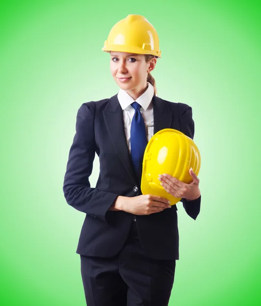 Young businesswoman with hard hat against gradient — Stock Photo, Image