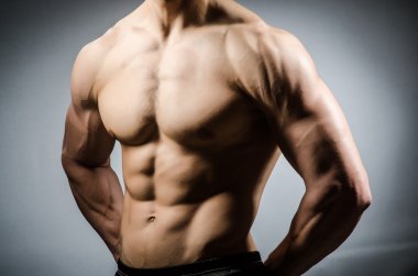 Kaslı adam karanlık stüdyoda poz veriyor.