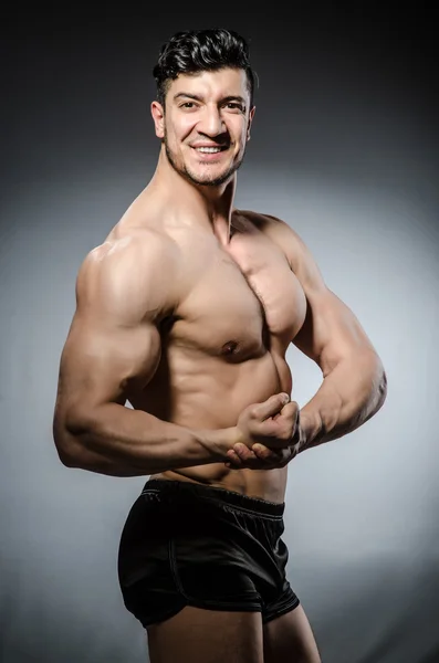 Muscular man posing in dark studio — Stock Photo, Image