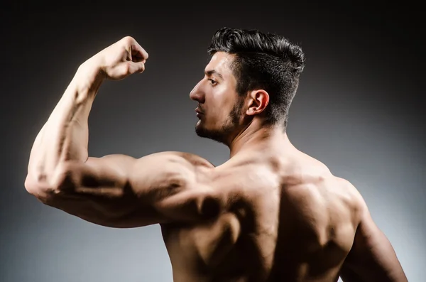 Muscular man posing in dark studio — Stock Photo, Image