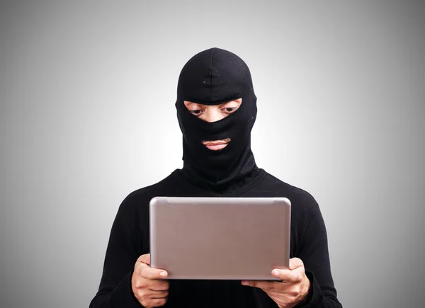 Hacker with computer wearing balaclava — Stock Photo, Image