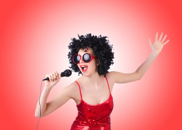 Pop star with mic in red dress against gradient — Stock Photo, Image