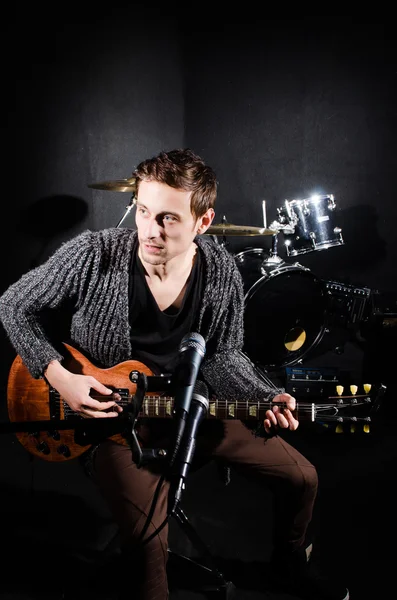 Man playing guitar in dark room — Stock Photo, Image