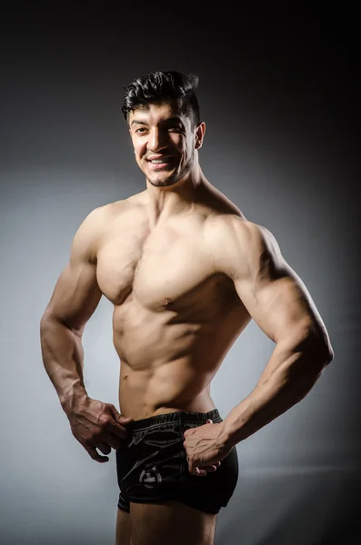 Muscular man posing in dark studio — Stock Photo, Image