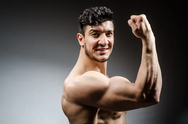 Hombre musculoso posando en estudio oscuro — Foto de Stock