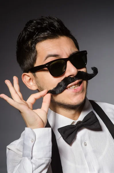 Ung man med falsk mustasch isolerade på grå — Stockfoto