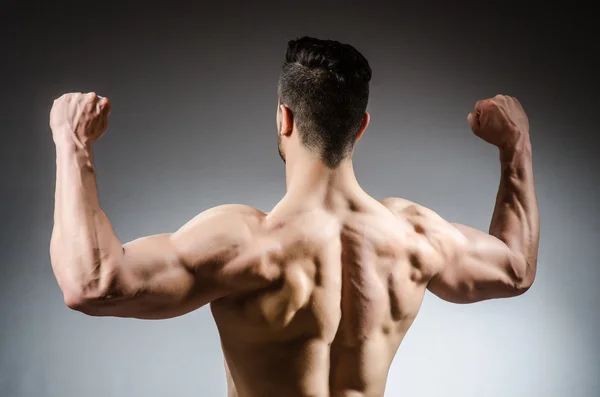 Muscular man posing in dark studio — Stock Photo, Image