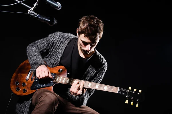 Hombre tocando la guitarra en habitación oscura — Foto de Stock