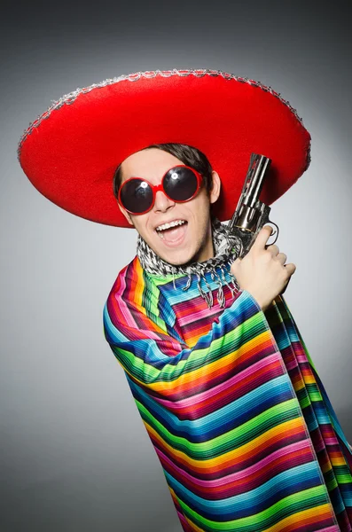 Człowiek w żywe meksykański Ponczo trzymając pistolet na szarym tle — Zdjęcie stockowe