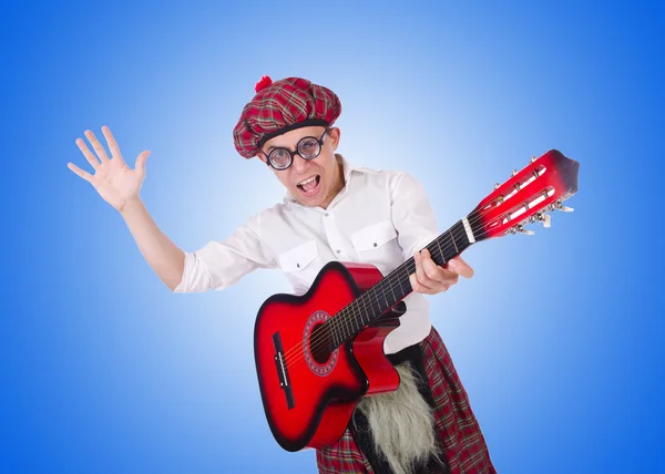 Смешной шотландец с гитарой против градиента — стоковое фото