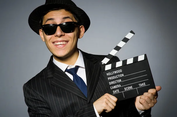 Giovane in abito elegante tenere clapperboard contro grigio — Foto Stock