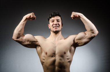 Kaslı adam karanlık stüdyoda poz veriyor.