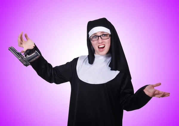 Nun with handgun on purple — Stock Photo, Image