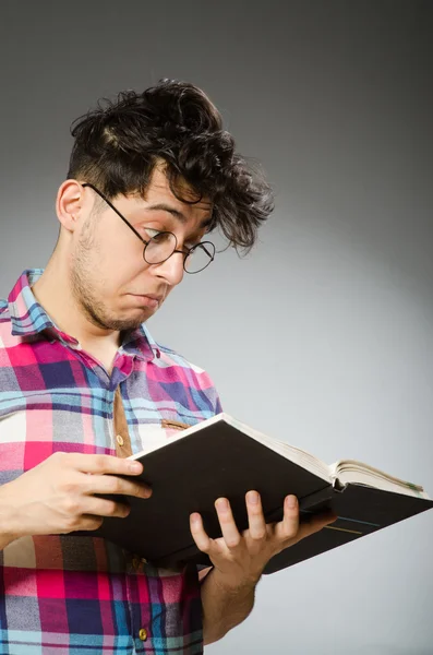 Estudiante divertido con libro sobre fondo gris —  Fotos de Stock