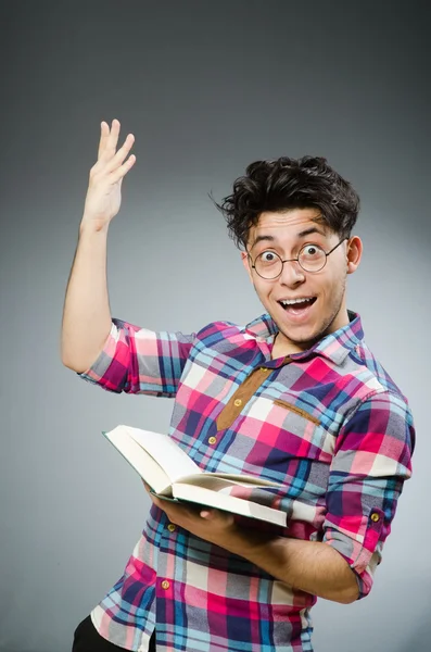 Étudiant drôle avec livre sur fond gris — Photo