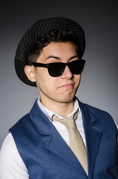 Jonge man in blauwe vest en hoed tegen grijs — Stockfoto