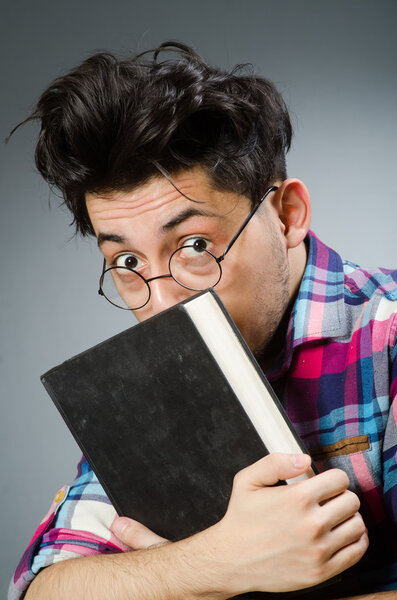 Funny student with book against gray background