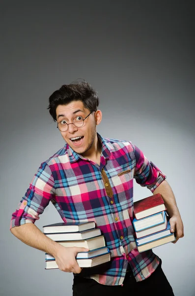 Estudante engraçado com muitos livros — Fotografia de Stock