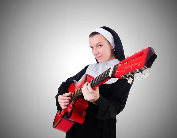 Freira tocando guitarra contra o gradiente — Fotografia de Stock