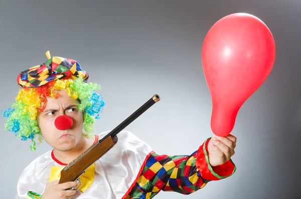 Клоун с воздушным шаром и винтовкой в смешной концепции — стоковое фото
