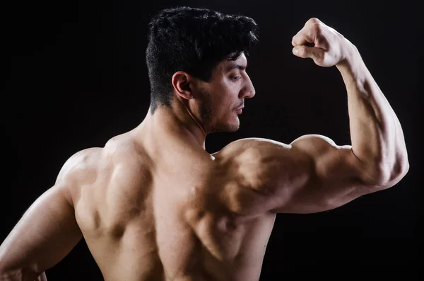 Homem muscular posando em estúdio escuro — Fotografia de Stock