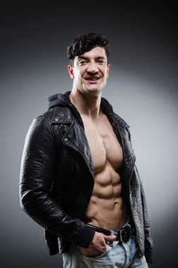 Kaslı adam karanlık stüdyoda poz veriyor.