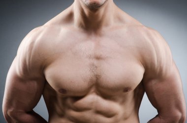 Kaslı adam karanlık stüdyoda poz veriyor.