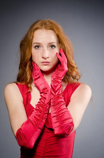 Dívka v červených šatech proti šedi — Stock fotografie